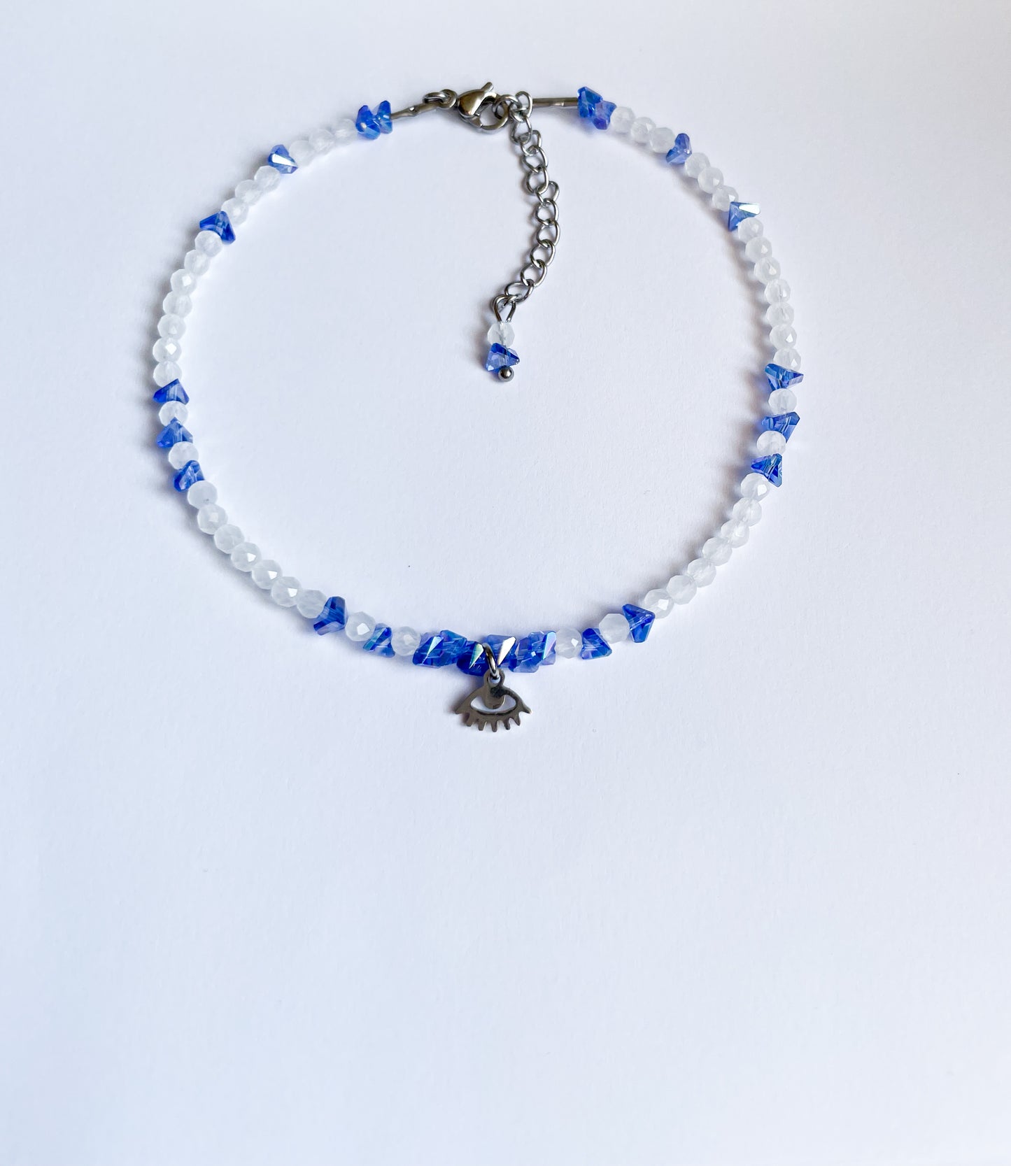 Гривна за глезен със сини и бели кристали и висулка око