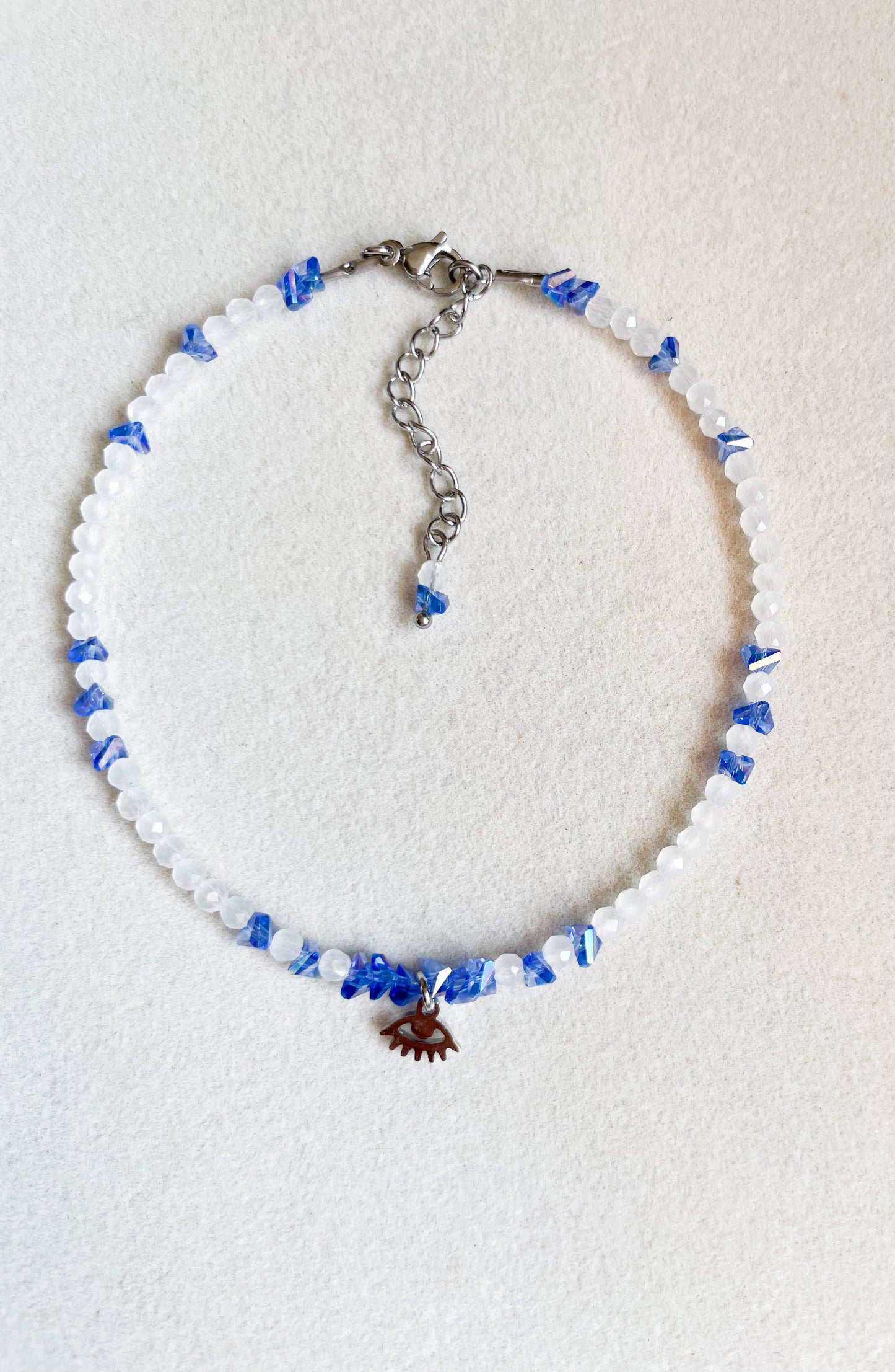 Гривна за глезен със сини и бели кристали и висулка око